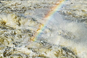 Splashing water waves with rainbow on the fast river