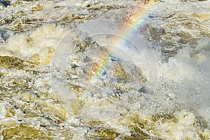 Splashing water waves with rainbow on the fast river