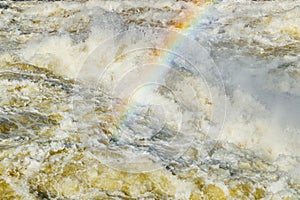 Splashing water waves with rainbow on the fast river