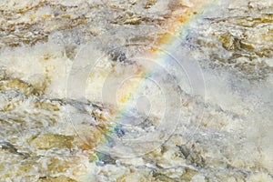 Splashing water waves with rainbow on the fast river