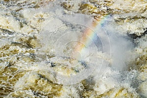 Splashing water waves with rainbow on the fast river