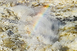 Splashing water waves with rainbow on the fast river