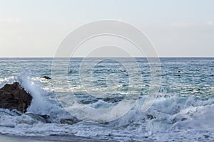 Splashing wave breaking on rock, with swirling foam from breaking wave and returning backwash