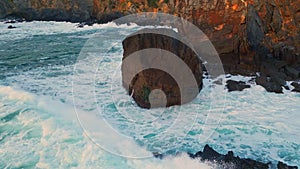 Splashing waves crashing rocks closeup. Ocean surf making white foam coastline photo