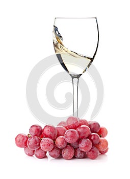 Splashing white wine in a glass and grapes