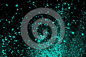 A splatter of green blue colored pigment powder on black background