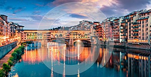 Splendid medieval arched river bridge with Roman origins - Ponte Vecchio over Arno river. Colorful spring sunset view of Florence