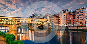 Splendid medieval arched river bridge with Roman origins - Ponte Vecchio over Arno river. Colorful spring sunset view of Florence