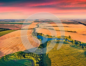 Splendid summer view from flying drone of river in the shape of tree among the field of wheat.