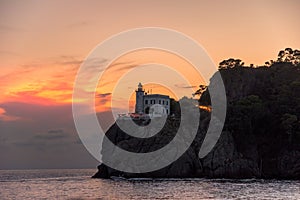 A splendid sunset by the historic lighthouse, Faro di Portofino, at Portofino, Liguria, Italy.