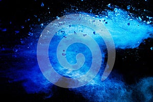 Split debris of stone exploding with blue powder against black background