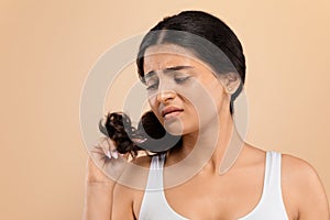 Split Ends. Upset indian woman looking at her damaged hair