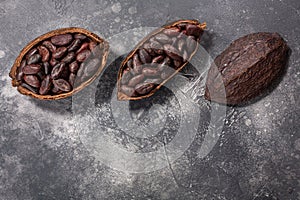 Split fermented cocoa pod with shelled cacao beans atop grey, top view, copy space