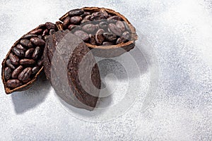 Split fermented cocoa pod with shelled cacao beans atop light grey backdrop, top view,  copy space