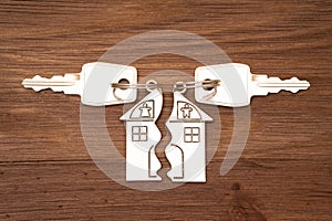 Split house shaped keychains on a wooden background photo