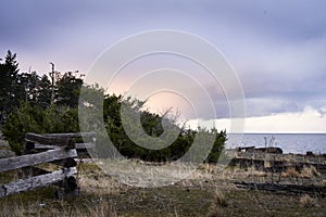 A split log wooden fence leading to the ocean beach and beautiful twilight clouds.