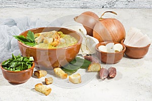 Split pea soup in rustic bowl decorated with fresh green leaves,garlic and slices of lard