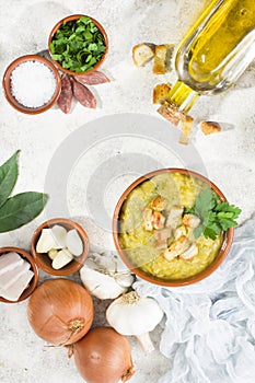 Split pea soup in rustic bowl decorated with fresh green leaves,garlic and slices of lard