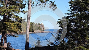 Split Rock Ligthhouse and Lake Superior in Minnesota seen between trees.