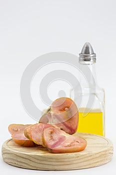 Split tomato on wooden board and an oil can