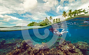 Split underwater photo of a girl snorkeling with mask in tropical ocean enjoying summer vacation on exotic island