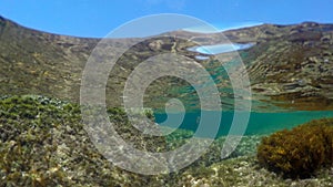 Split underwater view of Alghero rocky shore on a clear day. Sardinia