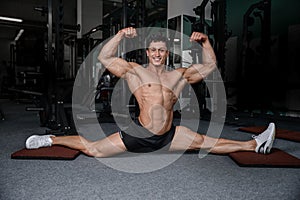 Splits stretches man stretching legs in the gym handsome fitness