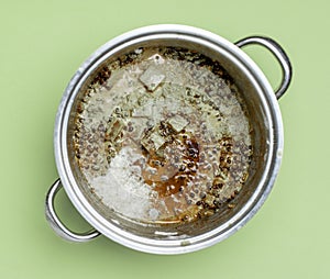 Spoiled food in a steel pot, isolated on green mold color background. Top view. Food spoilage.