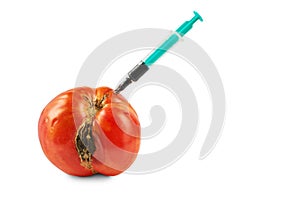 Spoiled tomato with stuck syringe isolated on white background.