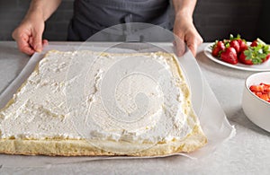 Sponge cake base spread with whipped cream for making a swiss roll