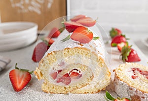 Sponge cake with strawberries and whipped cream rolled up to a swiss roll