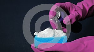 Sponge in male hand in magenta rubber glove. White foam splashes out of the spray can.