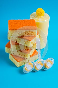 Sponges for cleaning and washing dishes, toilet block and detergent in a transparent plastic bottle on a blue background