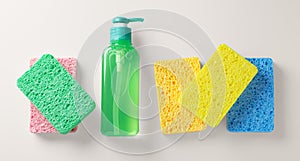 Sponges with green dish washing liquid on light beige background