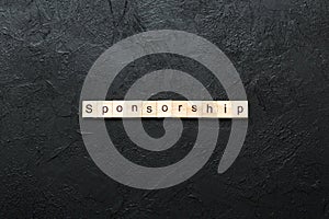 Sponsorship word written on wood block. Sponsorship text on table, concept photo