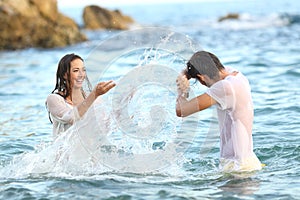 Spontaneous couple joking throwing water on the beach photo