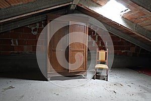 Spooky attic of the uninhabited house with an old wooden wardrob