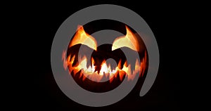 Spooky Halloween jack o lantern with scary face carved out of a pumpkin glowing with flickering light and emitting smoke