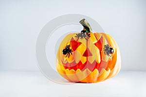 Spooky halloween orange pumpkin, Jack O Lantern with spiders on it on the white background with copy space. Happy