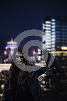 Spooky man with crow on night city background. Halloween concept