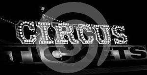 Spooky old dimly lit circus sign with light bulbs in the dark over a ticket stand in black and white. Typical view of an entrance