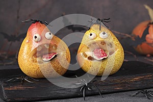 Spooky pear monsters for Halloween party on wooden board decorated spiders, Halloween Fruit Serving Idea