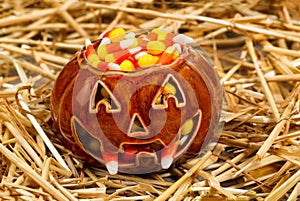 Spooky pumpkin filled with candy corn on straw