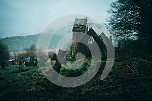 Spooky ruined church surrounded by a graveyard on a misty winters day in the English countryside