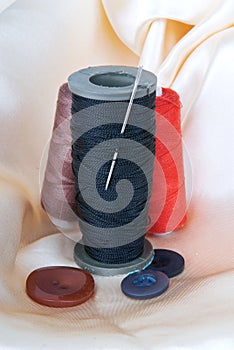 Spool of black thread with a needle and buttons