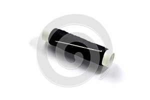 Spool of black thread and needle isolated on a white background