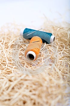 Spool of blue and orange sewing thread with needle