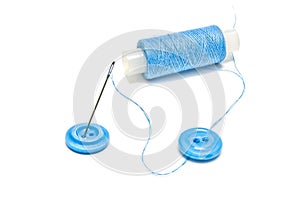 Spool of blue thread and buttons on white