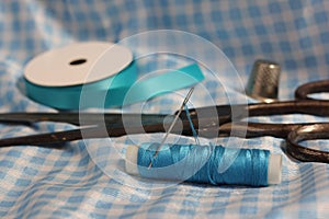 Spool of Blue Thread, Thimble and Needle on Blue and White Fabric