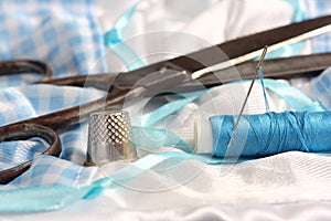 Spool of Blue Thread, Thimble and Needle on Blue and White Fabric